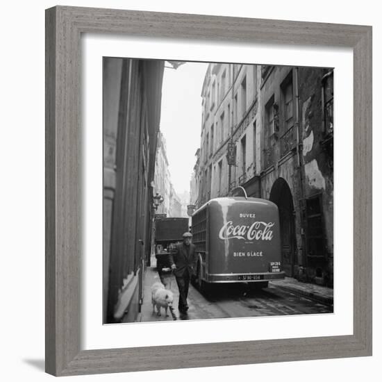 A Man Walks His Dog Beside a Bus with Coca Cola Advertisement, France, 1950-Mark Kauffman-Framed Photographic Print