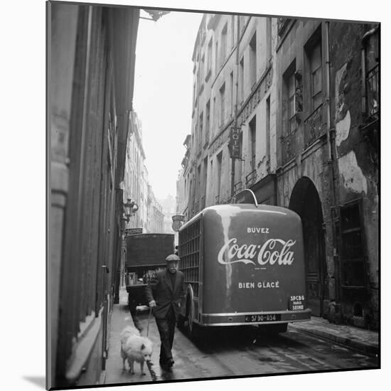 A Man Walks His Dog Beside a Bus with Coca Cola Advertisement, France, 1950-Mark Kauffman-Mounted Photographic Print