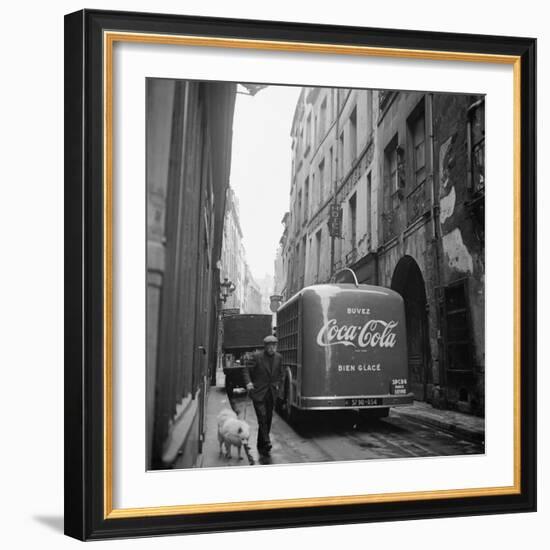 A Man Walks His Dog Beside a Bus with Coca Cola Advertisement, France, 1950-Mark Kauffman-Framed Photographic Print