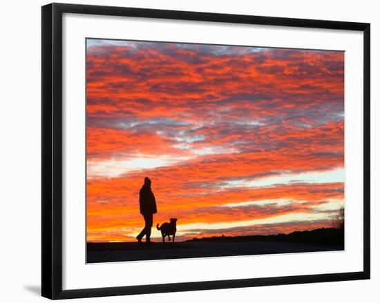 A Man Walks His Dog Under a Red Sky-null-Framed Photographic Print