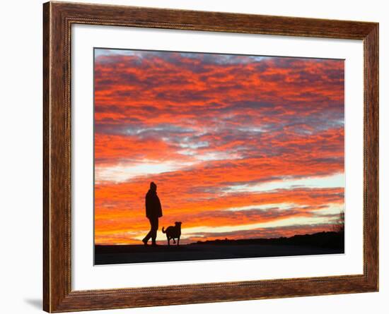 A Man Walks His Dog Under a Red Sky-null-Framed Photographic Print