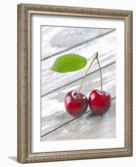 A Pair of Cherries with a Leaf on a Wooden Table-Jürgen Klemme-Framed Photographic Print