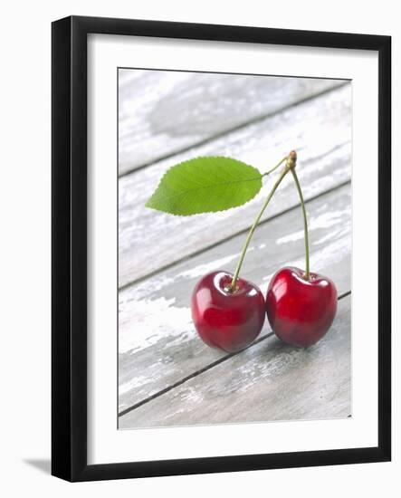 A Pair of Cherries with a Leaf on a Wooden Table-Jürgen Klemme-Framed Photographic Print