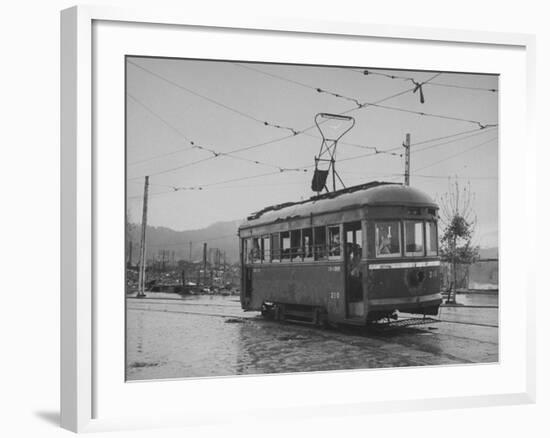 A Passenger-Filled Streetcar Traveling Through a Bomb-Damaged City-null-Framed Photographic Print