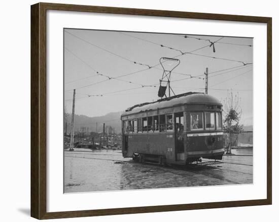 A Passenger-Filled Streetcar Traveling Through a Bomb-Damaged City-null-Framed Photographic Print