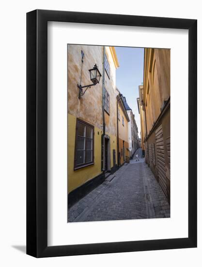 A pedestrian walks the streets of Stockholm's colorful and historic Gamla Stan district, Stockholm,-Jon Reaves-Framed Photographic Print