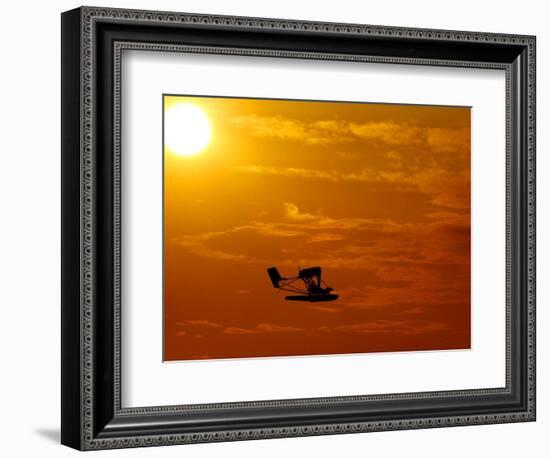 A Pilot Flies a Small Plane Past the Setting Sun Over Lake Winnipesaukee-null-Framed Photographic Print