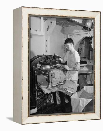 A Sailor Pressing Uniform Trousers in the Tailor Shop of a US Navy Cruiser-null-Framed Premier Image Canvas