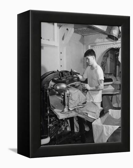 A Sailor Pressing Uniform Trousers in the Tailor Shop of a US Navy Cruiser-null-Framed Premier Image Canvas