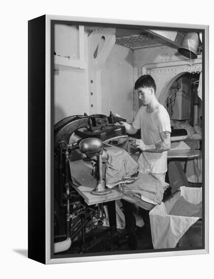 A Sailor Pressing Uniform Trousers in the Tailor Shop of a US Navy Cruiser-null-Framed Premier Image Canvas