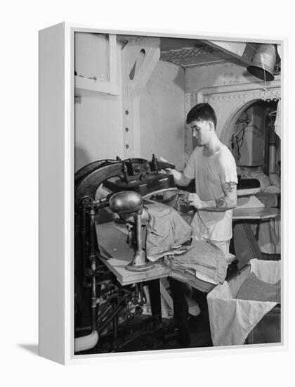 A Sailor Pressing Uniform Trousers in the Tailor Shop of a US Navy Cruiser-null-Framed Premier Image Canvas