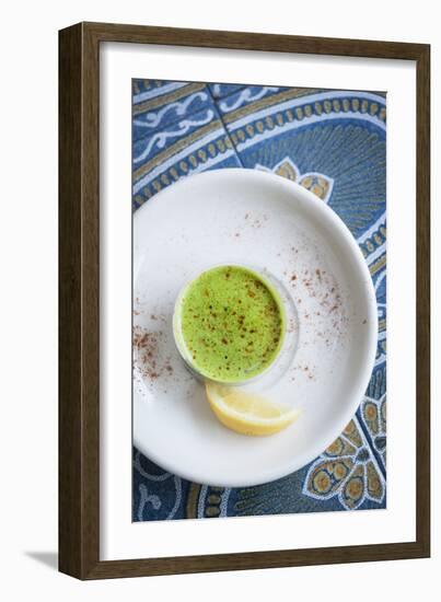 A Shot Of Wheat Grass In A Small Cup On A White Plate Served With A Lemon Wedge And Cayenne Pepper-Shea Evans-Framed Photographic Print