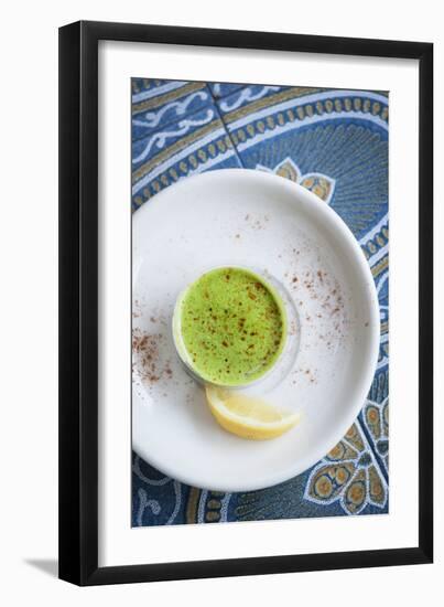 A Shot Of Wheat Grass In A Small Cup On A White Plate Served With A Lemon Wedge And Cayenne Pepper-Shea Evans-Framed Photographic Print