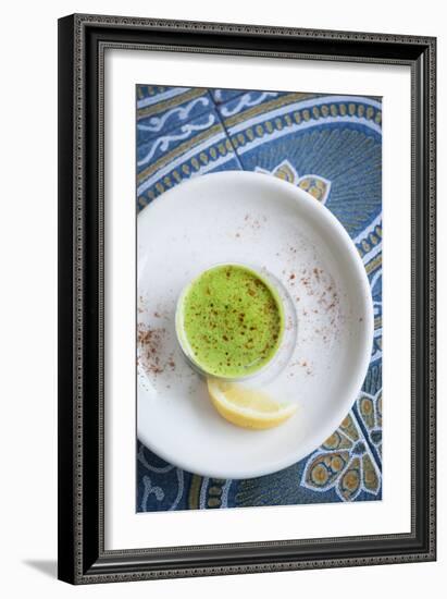 A Shot Of Wheat Grass In A Small Cup On A White Plate Served With A Lemon Wedge And Cayenne Pepper-Shea Evans-Framed Photographic Print