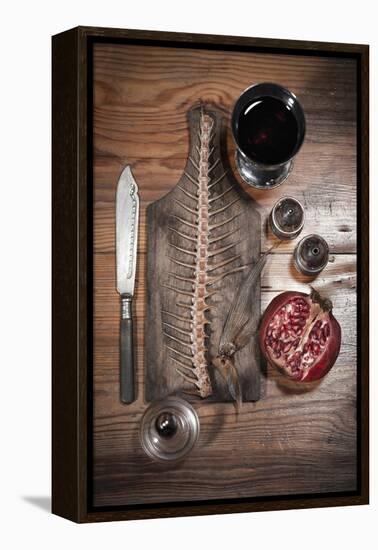 A Still Life Featuring a Fish Skeleton, Pomegranate and Red Wine-Komar-Framed Premier Image Canvas