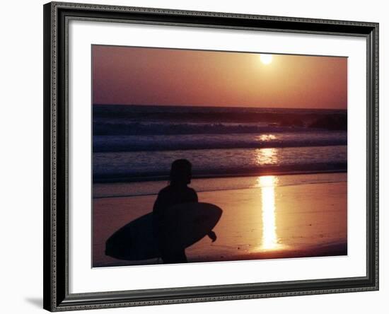 A Surfer is Silhouetted by the Setting Sun as He Leaves the Pacific Ocean on Venice Beach-null-Framed Photographic Print