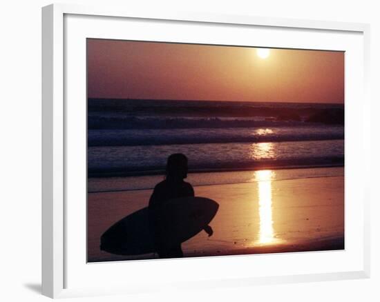 A Surfer is Silhouetted by the Setting Sun as He Leaves the Pacific Ocean on Venice Beach-null-Framed Photographic Print