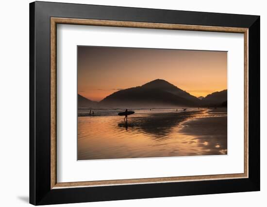 A Surfer Makes His Way Out of the Water at Sunset on Praia Do Itamambuca in Brazil-Alex Saberi-Framed Photographic Print