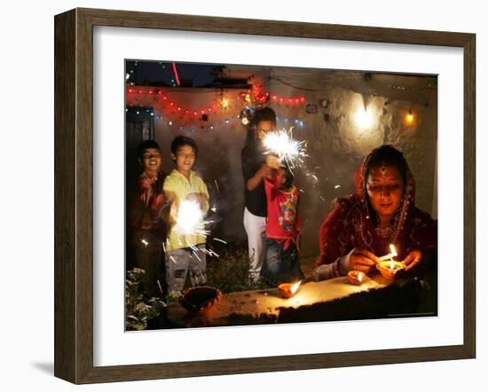 A Woman Lights Earthen Lamps as Children Ignite Firecrackers in New Delhi-Manish Swarup-Framed Photographic Print