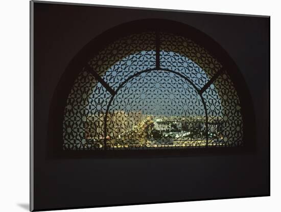 Abu Dhabi at night through the ornate Islamic-inspired metal grill on the roof of a tower-Werner Forman-Mounted Giclee Print