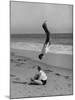 Acrobat/Actor, Russ Tamblyn Doing a Flip on Beach with Movie Actress Venetia Stevenson Watching Him-Allan Grant-Mounted Premium Photographic Print