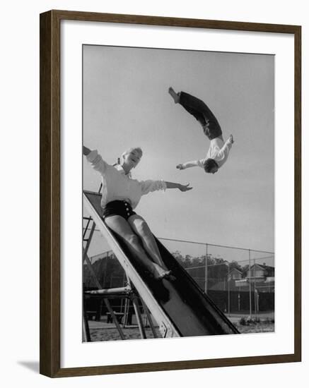 Acrobat and Actor Russ Tamblyn Doing a Flip at a Playground with Movie Actress Venetia Stevenson-Allan Grant-Framed Premium Photographic Print