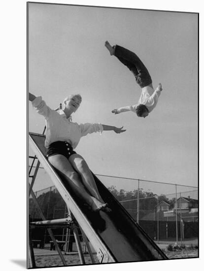Acrobat and Actor Russ Tamblyn Doing a Flip at a Playground with Movie Actress Venetia Stevenson-Allan Grant-Mounted Premium Photographic Print