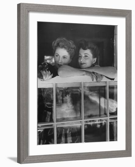 Actress Joan Fontaine with Actress Sister Olivia de Havilland Looking Out of Open Window at Home-Bob Landry-Framed Premium Photographic Print