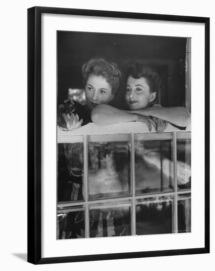 Actress Joan Fontaine with Actress Sister Olivia de Havilland Looking Out of Open Window at Home-Bob Landry-Framed Premium Photographic Print
