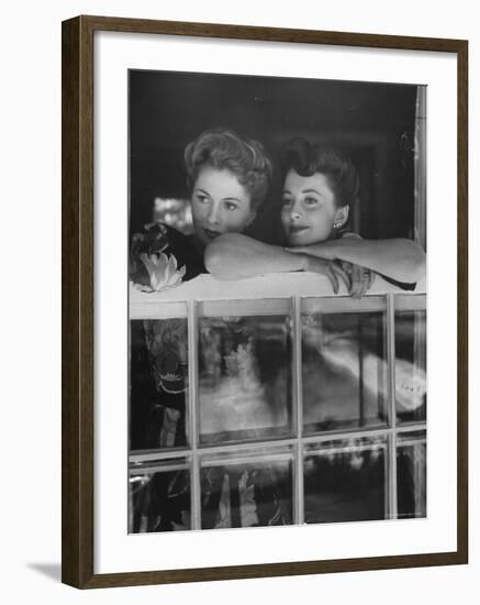 Actress Joan Fontaine with Actress Sister Olivia de Havilland Looking Out of Open Window at Home-Bob Landry-Framed Premium Photographic Print