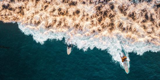 aerial drone photo of surfers riding pacific ocean waves in san