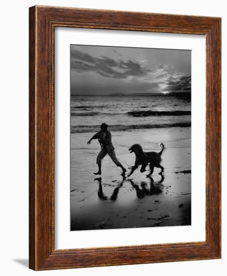 Afghan Dog Roaming across Beach with Girl at Sundown, During Preparation for Westminister Show-George Silk-Framed Photographic Print