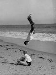 Acrobat/Actor, Russ Tamblyn Doing a Flip on Beach with Movie Actress Venetia Stevenson Watching Him-Allan Grant-Premium Photographic Print