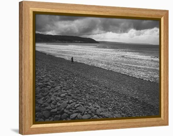Along British Coastline, Woman Walking on Pebbled Shore-Nat Farbman-Framed Premier Image Canvas