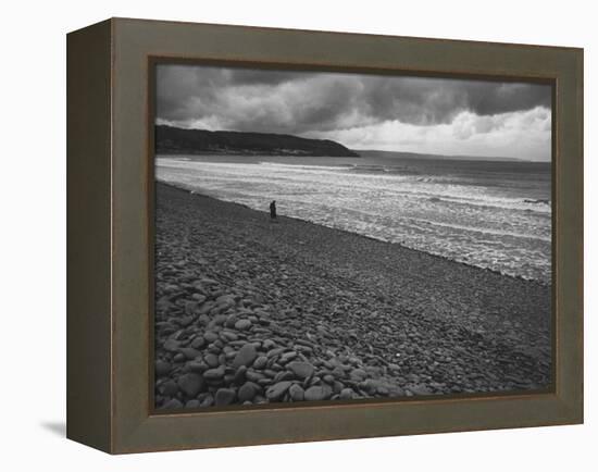 Along British Coastline, Woman Walking on Pebbled Shore-Nat Farbman-Framed Premier Image Canvas