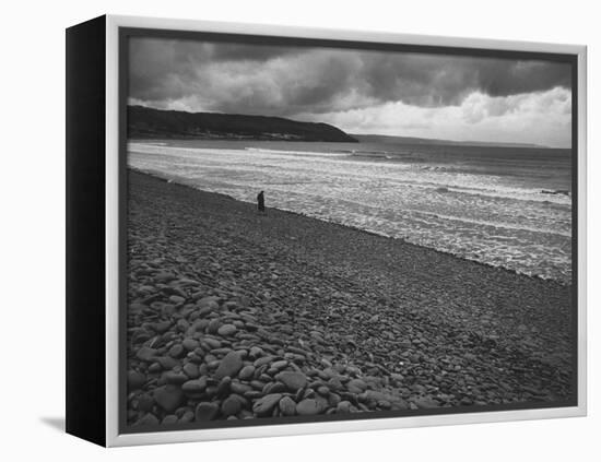Along British Coastline, Woman Walking on Pebbled Shore-Nat Farbman-Framed Premier Image Canvas