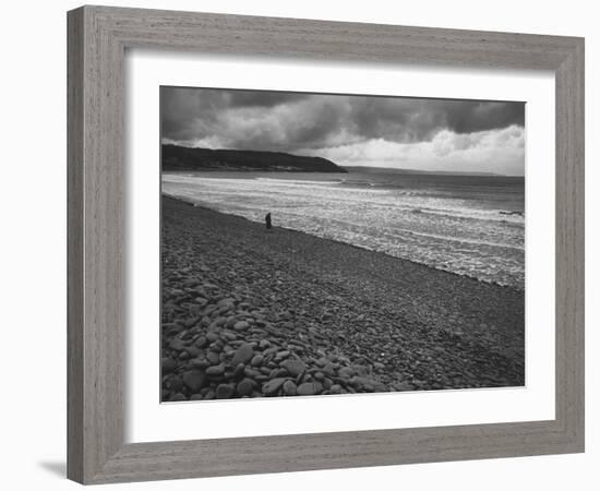 Along British Coastline, Woman Walking on Pebbled Shore-Nat Farbman-Framed Photographic Print