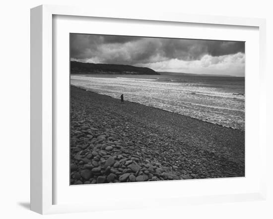 Along British Coastline, Woman Walking on Pebbled Shore-Nat Farbman-Framed Photographic Print