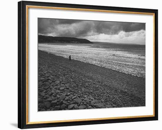Along British Coastline, Woman Walking on Pebbled Shore-Nat Farbman-Framed Photographic Print