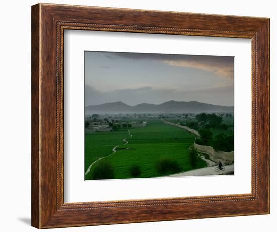 An Afghan Man Rides His Bicycle on a Dirt Road on the Northern Edge of Kabul, Afghanistan-David Guttenfelder-Framed Photographic Print