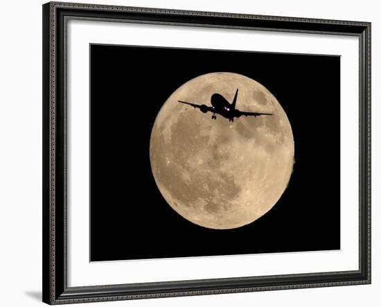 An Airliner is Silhouetted against a Full Moon-null-Framed Photographic Print