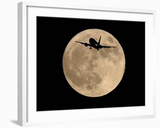 An Airliner is Silhouetted against a Full Moon-null-Framed Photographic Print