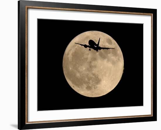 An Airliner is Silhouetted against a Full Moon-null-Framed Photographic Print