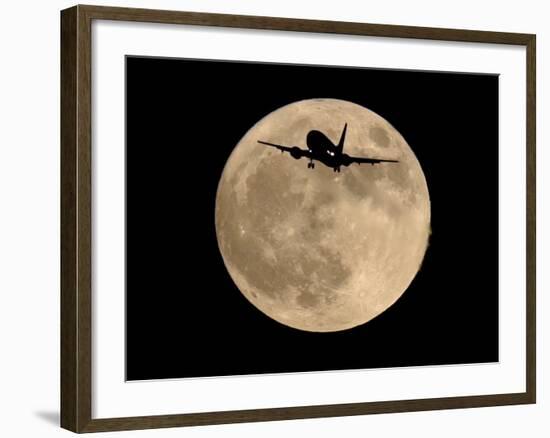 An Airliner is Silhouetted against a Full Moon-null-Framed Photographic Print