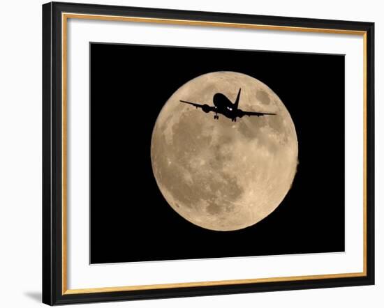 An Airliner is Silhouetted against a Full Moon-null-Framed Photographic Print