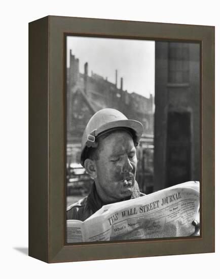 An Electrician Reads 'The Wall Street Journal' to Check His Stock Market Investments-null-Framed Stretched Canvas