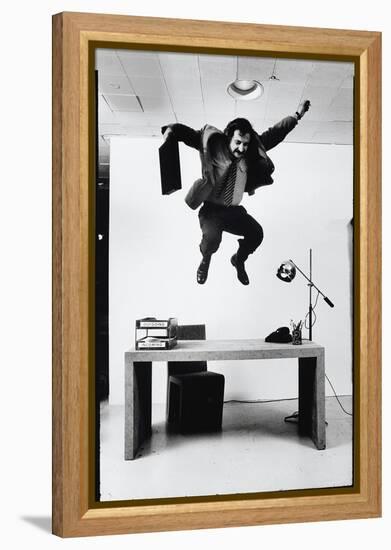 Architect and Designer Frank Gehry Jumping on a Desk in His Line of Cardboard Furniture-Ralph Morse-Framed Premier Image Canvas