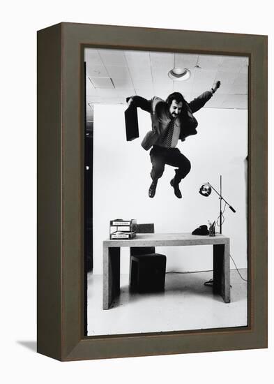 Architect and Designer Frank Gehry Jumping on a Desk in His Line of Cardboard Furniture-Ralph Morse-Framed Premier Image Canvas