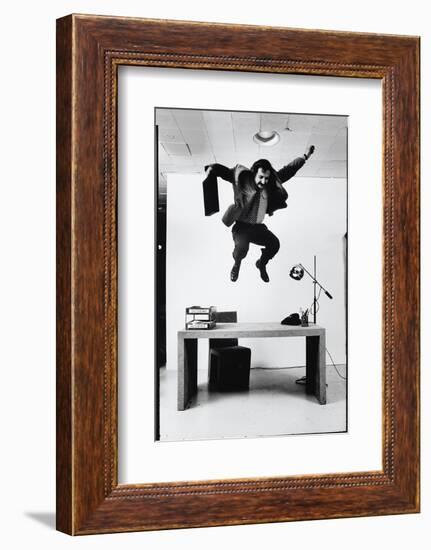 Architect and Designer Frank Gehry Jumping on a Desk in His Line of Cardboard Furniture-Ralph Morse-Framed Photographic Print