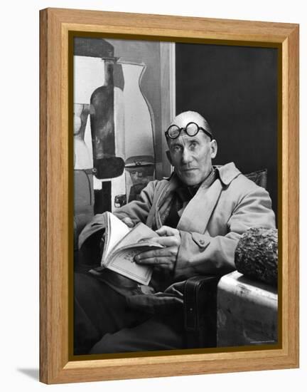 Architect Le Corbusier Sitting in Chair and Holding Book in Hands-Nina Leen-Framed Premier Image Canvas